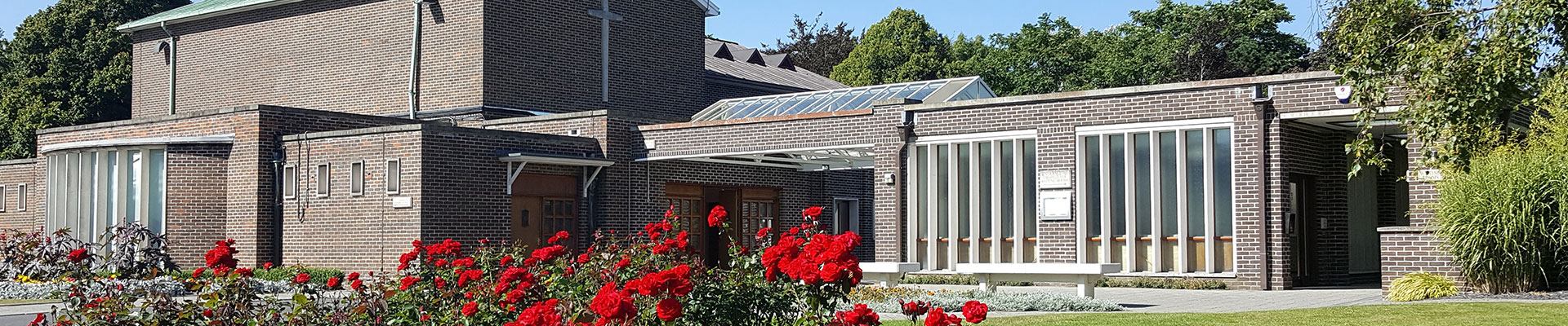 Photograph of the crematorium building with red roses in the foreground